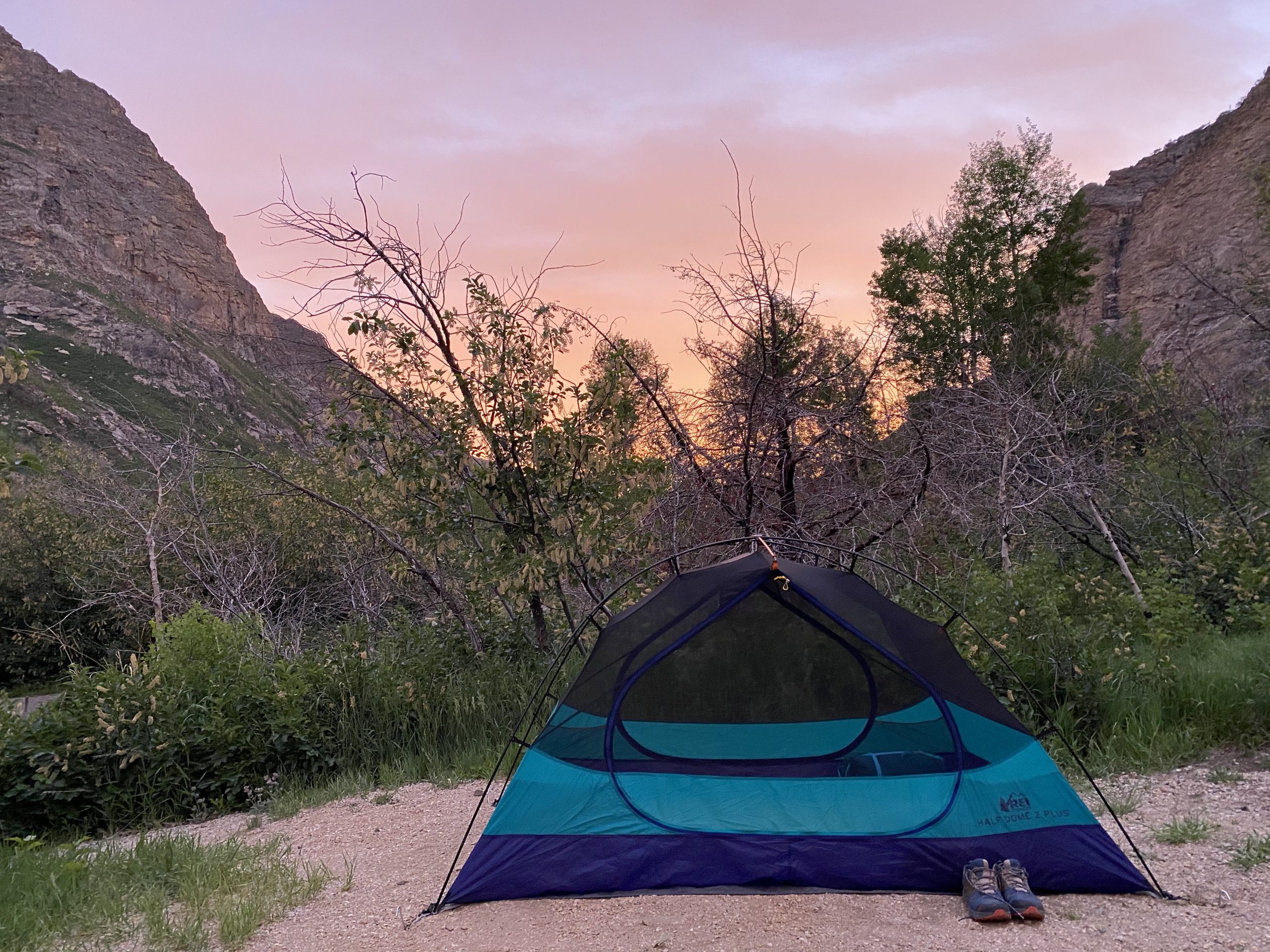 Picture of my tent in front of a pink sunset and some rocky canyon walls